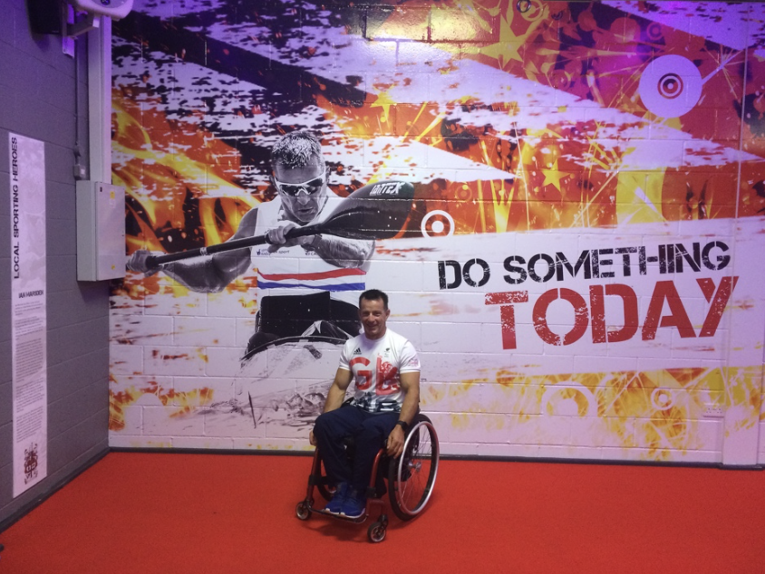 Ian, in front of a mural of himself with the caption "do something today".